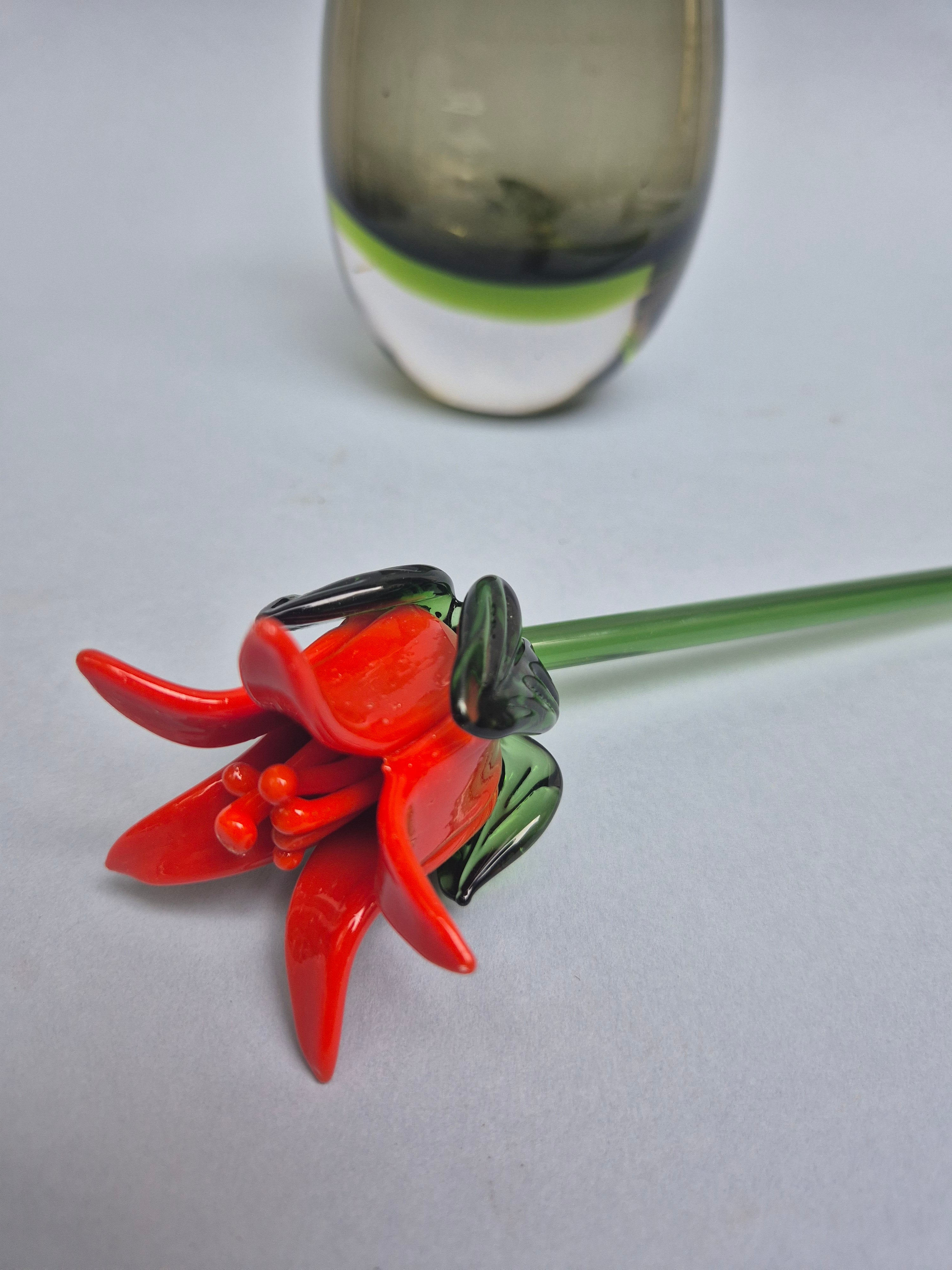 Red glass flower with green stem on a white background