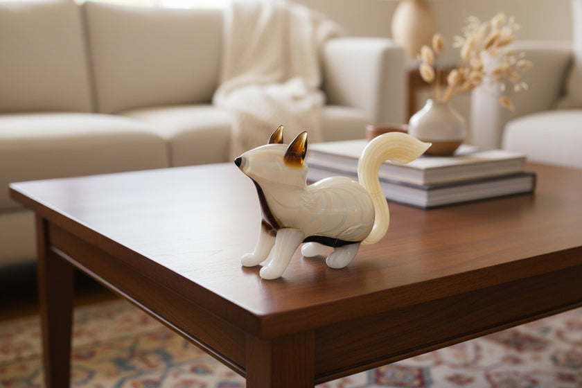 Glass fox figurine with a white base and black-tipped ears on a light beige background