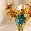 Decorative glass flowers in a clear vase on a textured surface