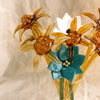 Decorative glass flowers in a clear vase on a textured surface