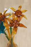 Glass sunflower decorations in a clear vase on a beige background