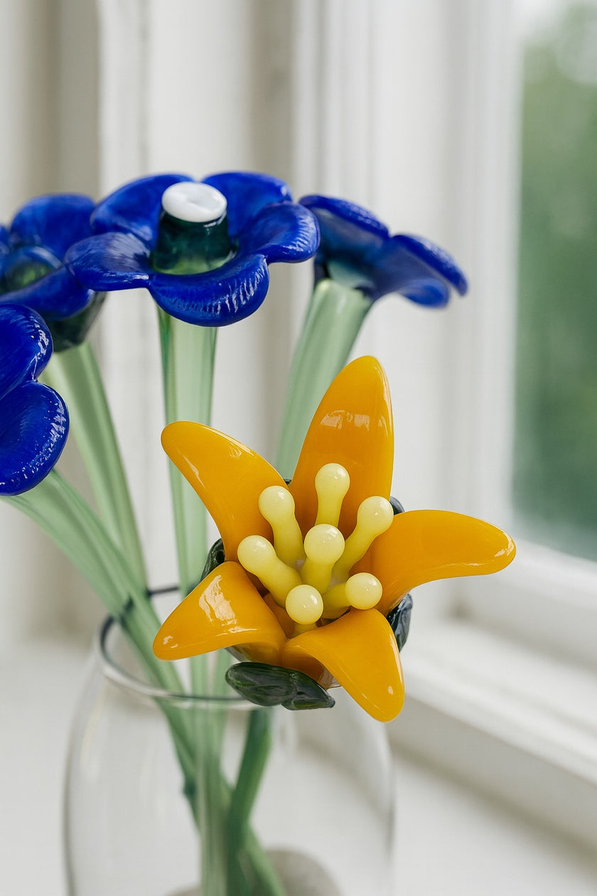 Vase with blue and yellow glass flowers on a windowsill