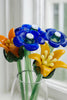 Bouquet of glass flowers in blue, orange, and yellow with a blurred white background