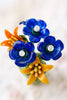 Colorful glass flower brooch with blue and orange flowers on a blurred background