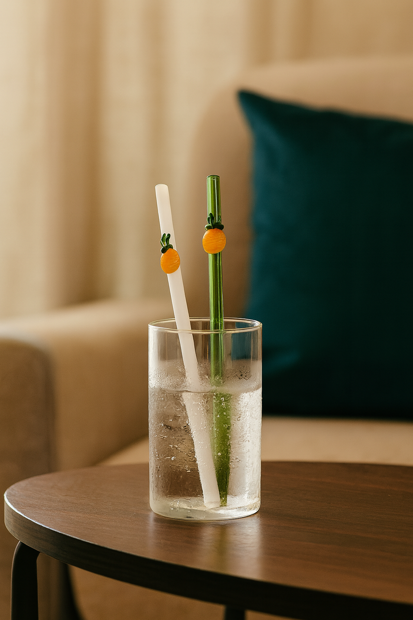 Glass of water with two decorative straws on a wooden table.