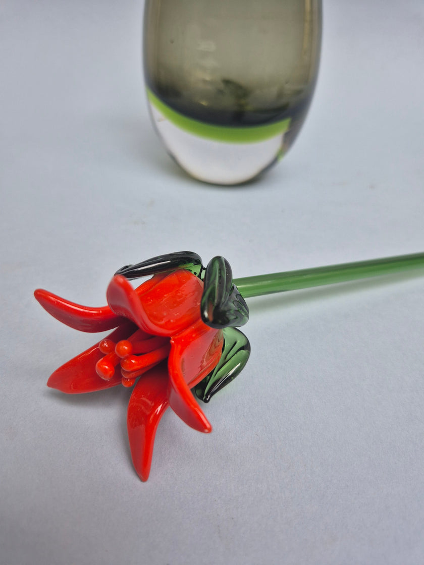 Red glass flower with green stem on a white background