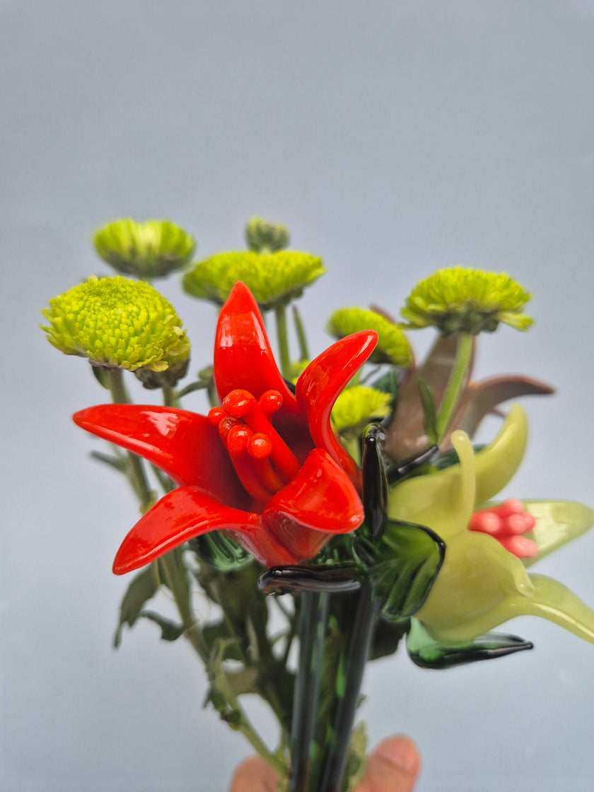 Close-up of a red flower-like object held by tongs against a gray background