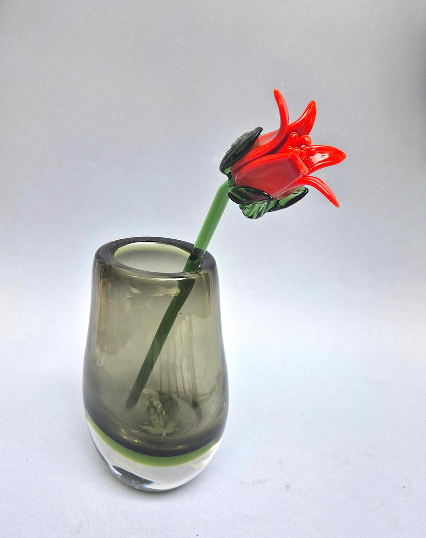 Glass vase with a red glass flower on a white background