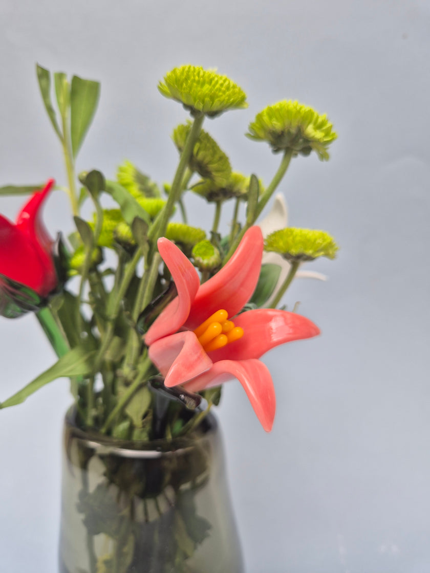 Bouquet of red and green flowers in a clear vase against a gray background