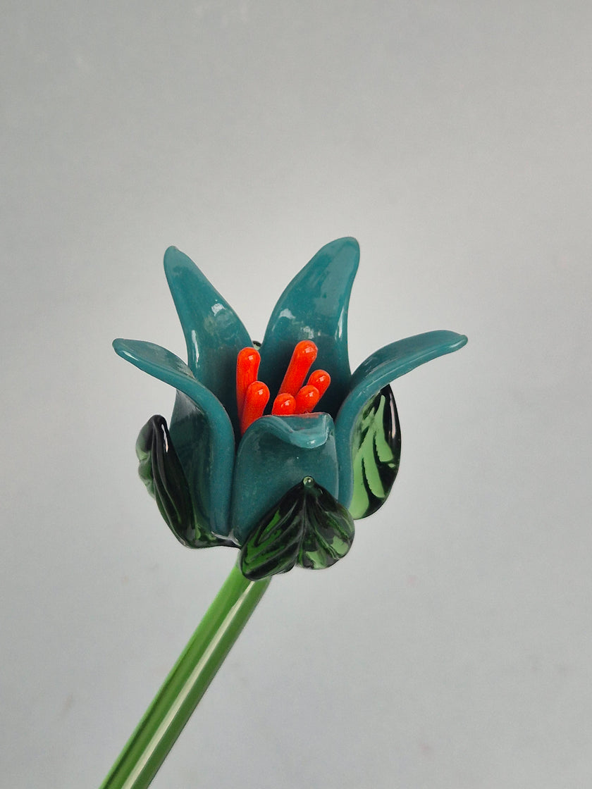 Glass flower with teal petals and orange stamens on a gray background