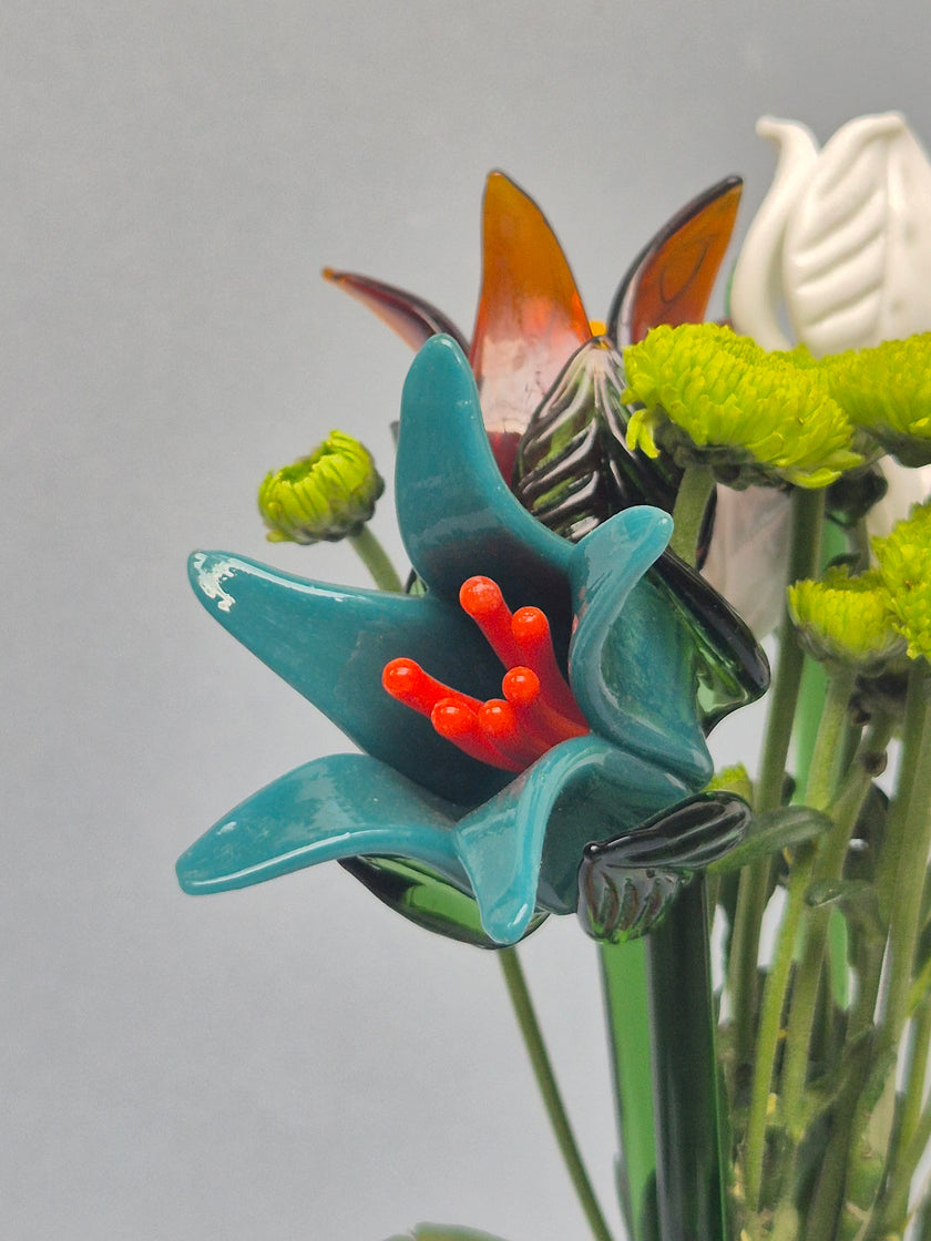 Close-up of a decorative flower with blue petals and red stamens on a gray background