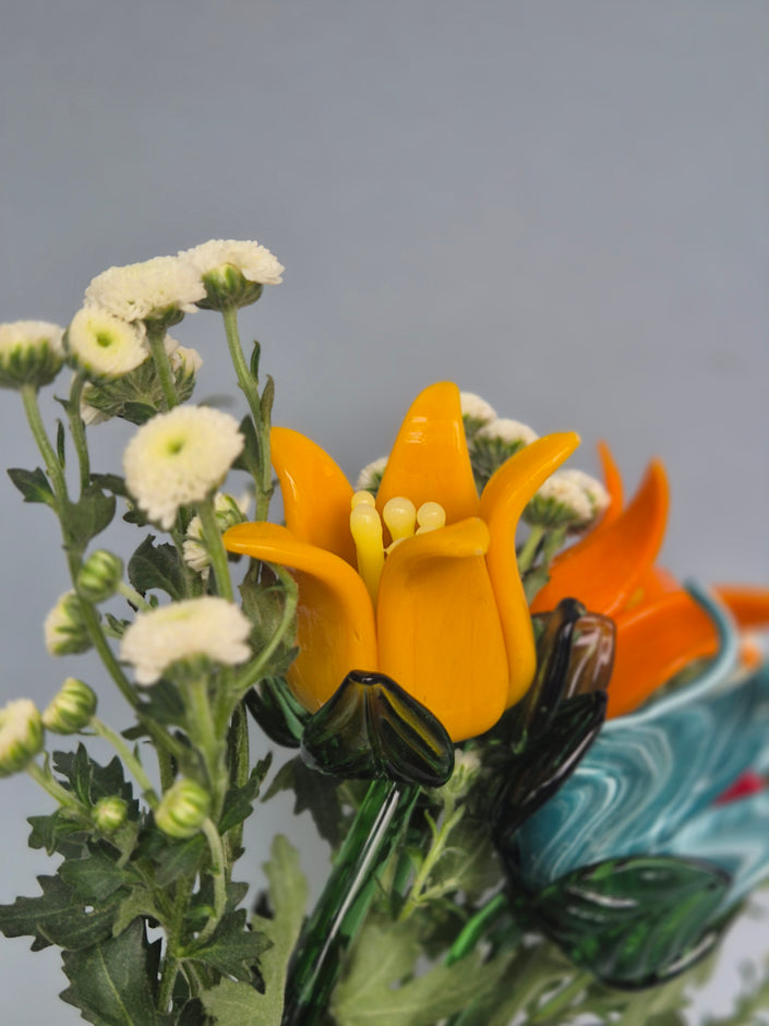 Close-up of a yellow flower with green leaves and white buds on a blurred background